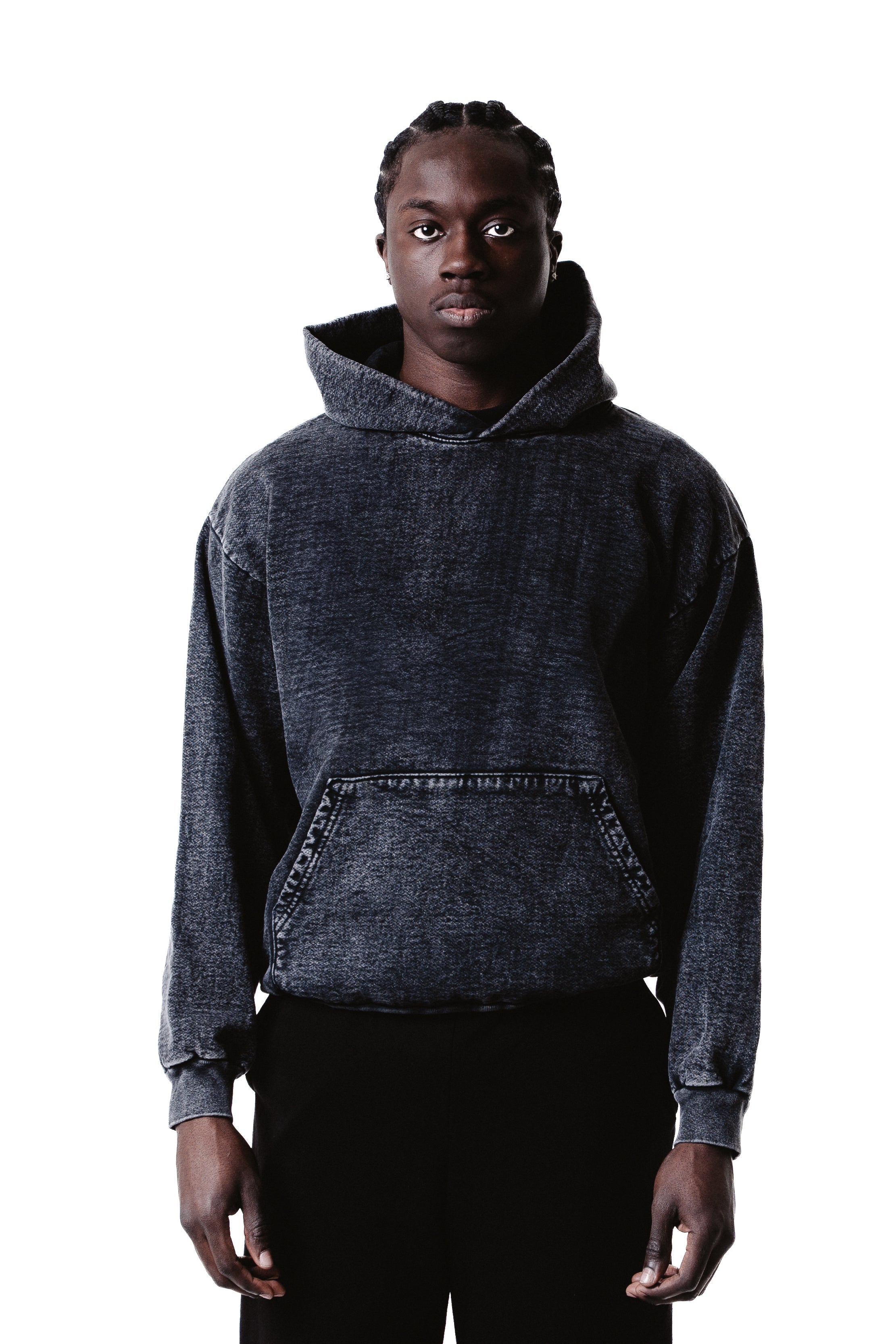 A person with braided hair wears the Mineral Wash Heavy Fleece Hoodie and black pants, standing facing forward against a plain white background.