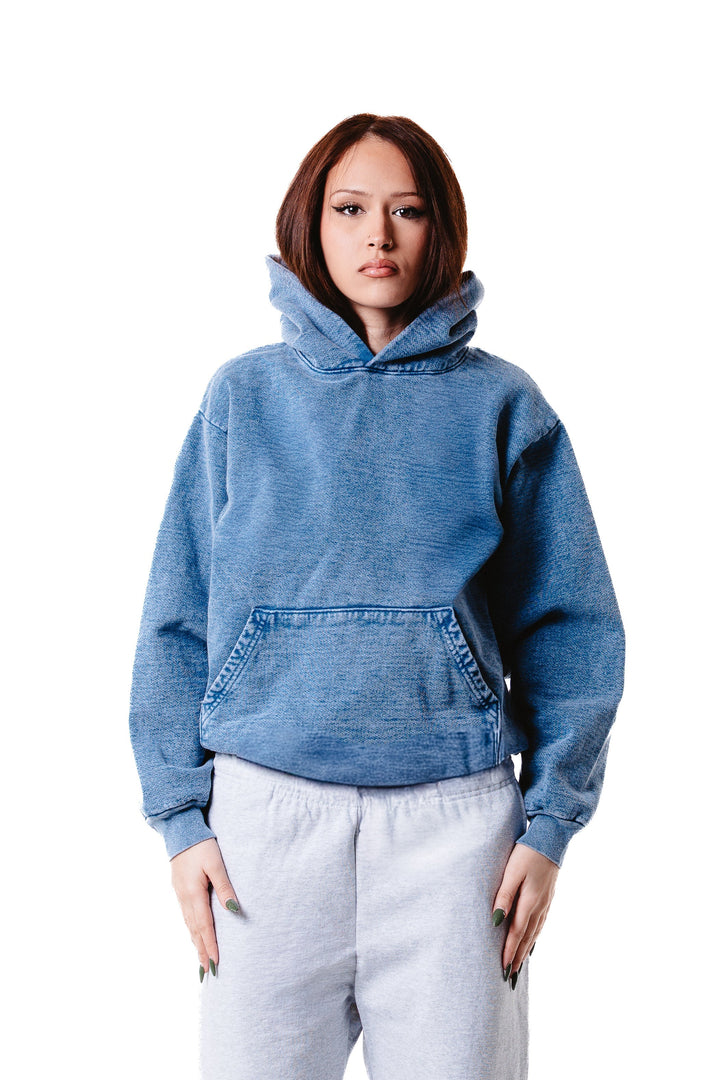 A person wears the Mineral Wash Heavy Fleece Hoodie in blue with light gray sweatpants, standing facing forward against a white background, arms at their sides and a neutral expression.