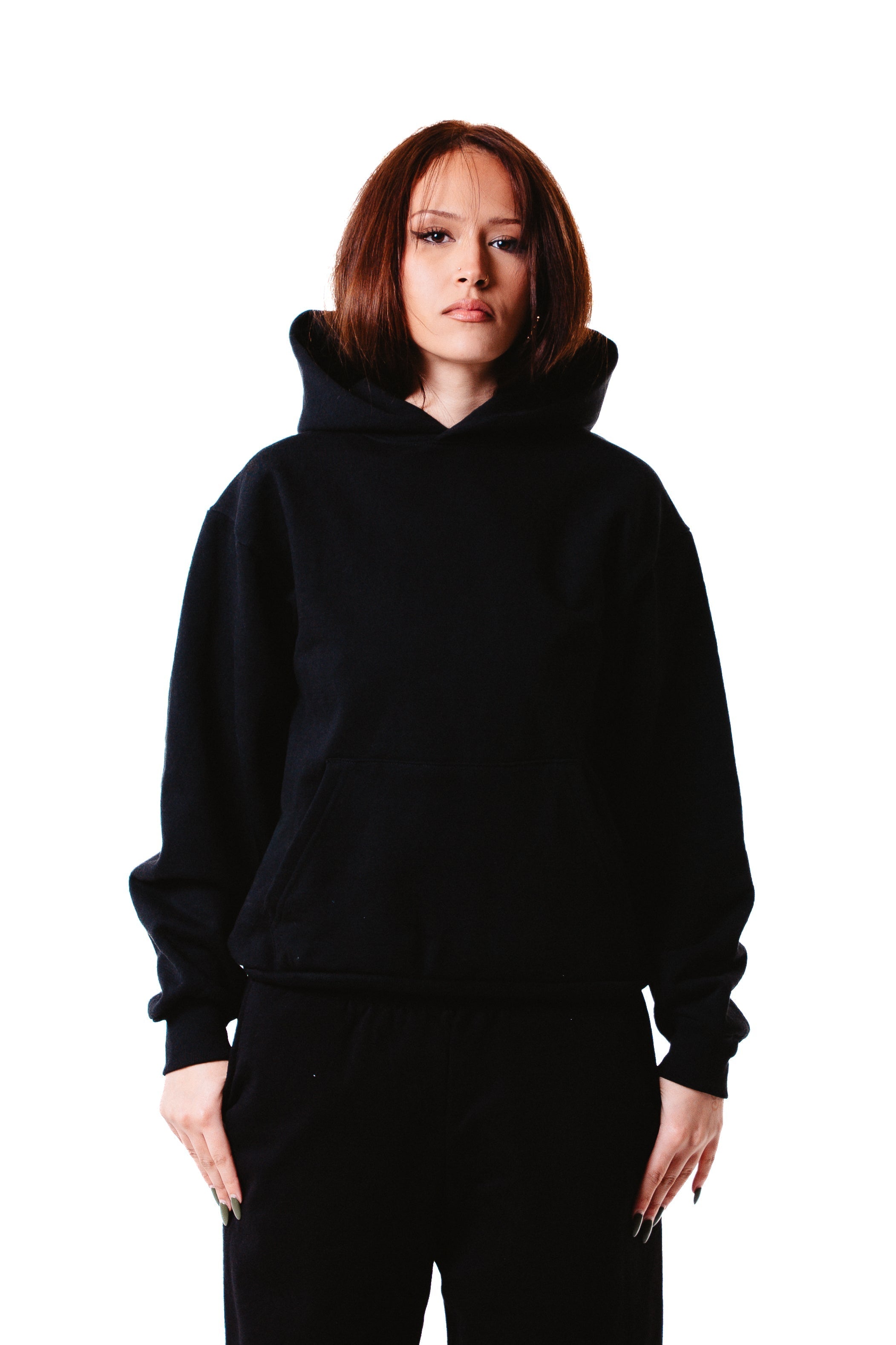 A person with straight, shoulder-length brown hair wears the Piece Dyed 14oz Heavy Fleece Hoodie and black pants, standing facing forward against a plain white background.